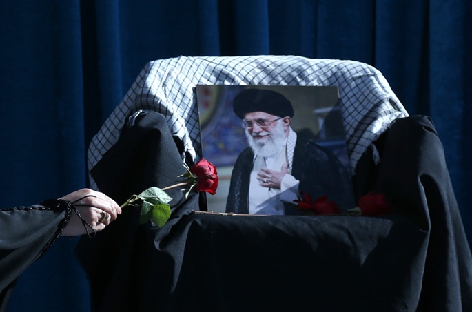 A person offers floral tribute during a rally to mourn for Iran's late Supreme Leader Ali Khamenei. File Photo: Xinhua/Shadati.